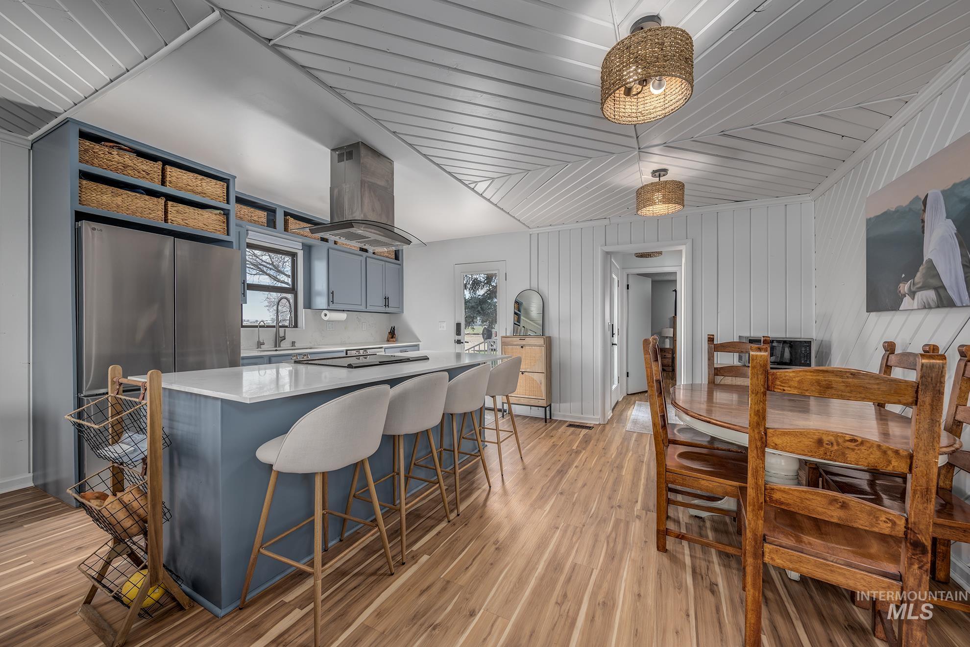 1009 County Road 70 Weiser, ID 83672 - Photo 7 of 48 Kitchen featuring a breakfast bar, island range hood, a center island, light wood-type flooring, and gray cabinetry