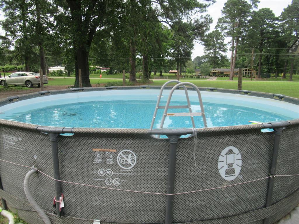 24133 Highway 157 Springhill, LA 71075 - Photo 9 of 19 Above-ground swimming pool featuring a textured exterior, ladder access, and surrounding green lawn