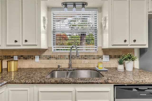 a kitchen with granite countertop a sink a stove and cabinets