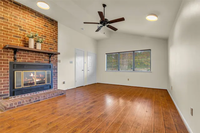 a view of empty room with wooden floor and fireplace