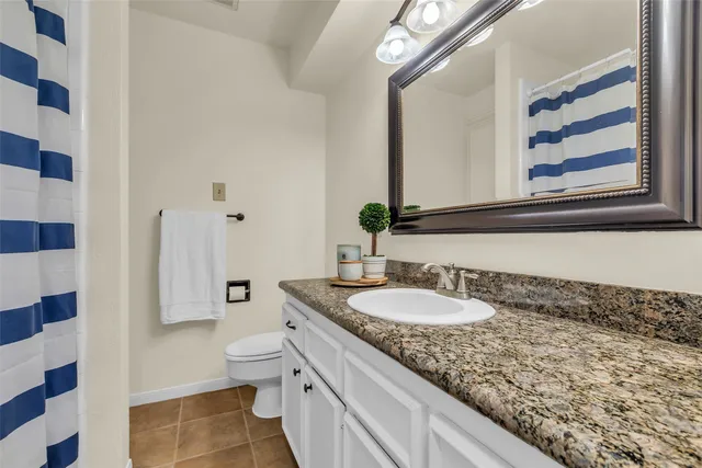 a bathroom with a granite countertop double vanity sink mirror and toilet