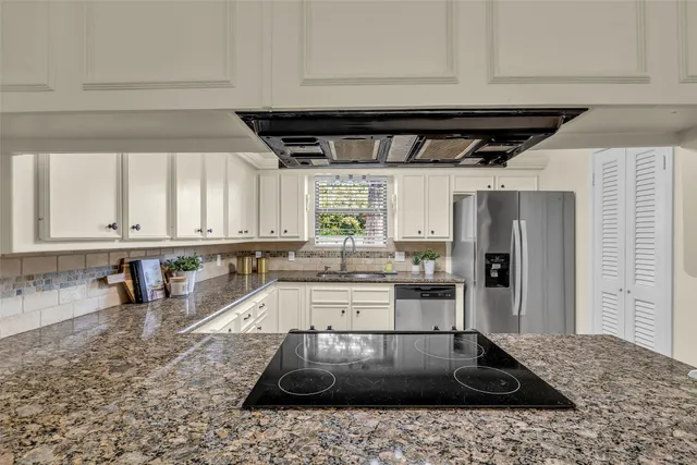 a kitchen with stainless steel appliances granite countertop a sink a stove and a refrigerator