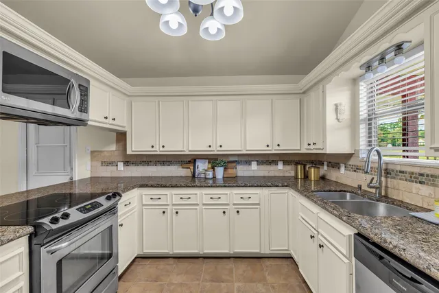 a kitchen with granite countertop a sink stainless steel appliances and cabinets