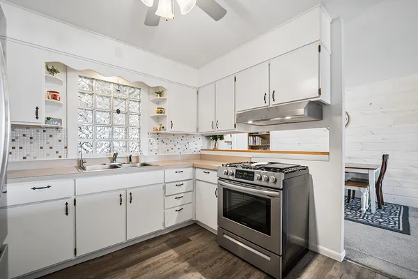 a kitchen with cabinets stainless steel appliances and wooden floor