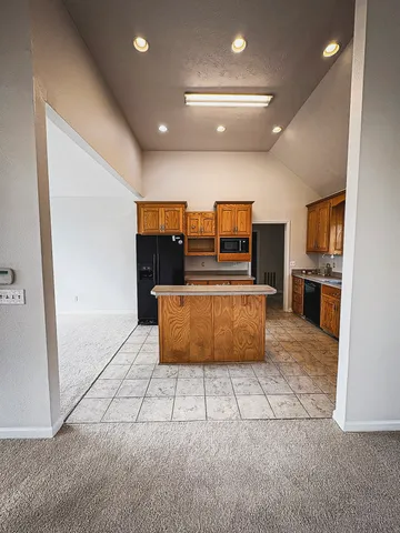 a large kitchen with stainless steel appliances kitchen island granite countertop a refrigerator and a stove top oven