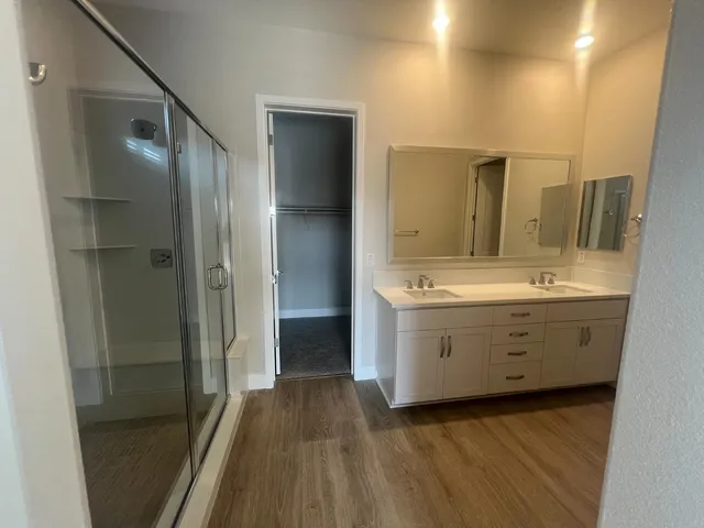 a bathroom with a double vanity sink a toilet and shower