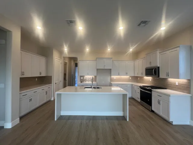 a large kitchen with stainless steel appliances a sink and cabinets
