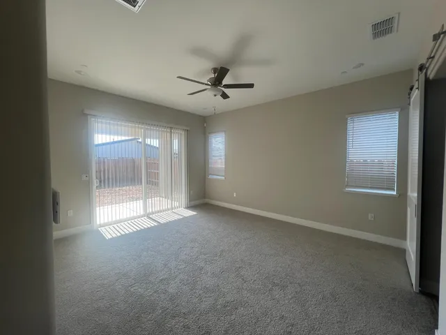 an empty room with windows and fan