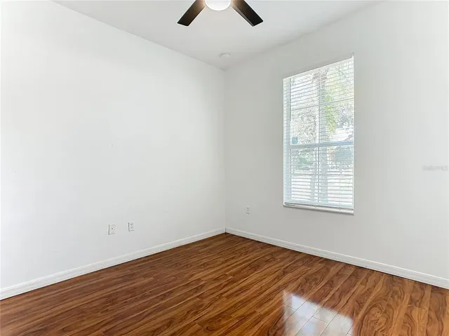 an empty room with a window and ceiling fan