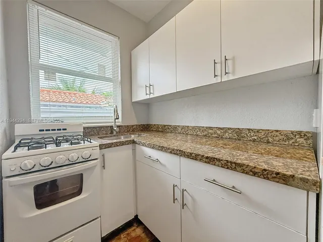 a kitchen with granite countertop white cabinets and white appliances