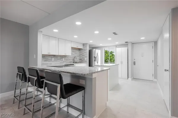 a large kitchen with granite countertop a counter top space and stainless steel appliances