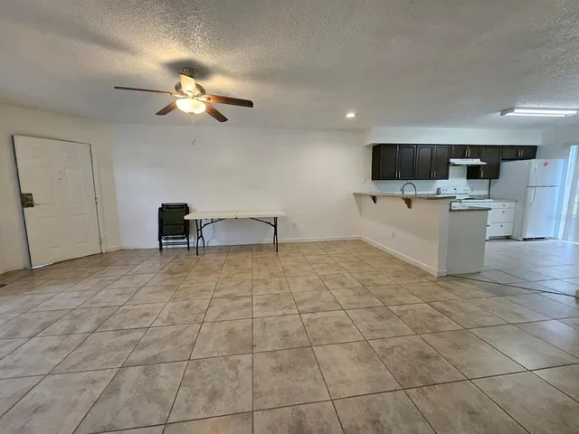 a view of a livingroom with kitchen furniture and a ceiling fan