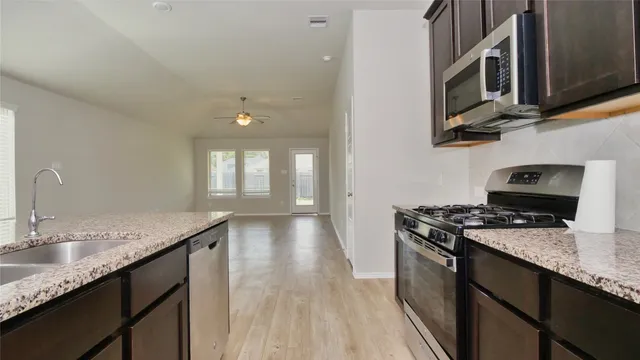a kitchen with stainless steel appliances granite countertop a sink stove and microwave