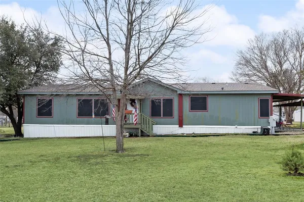 a house that has a big yard large trees with wooden fence