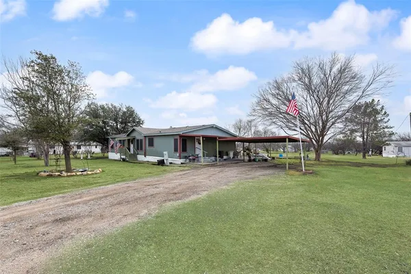 a view of a big house in front of a big yard with large trees