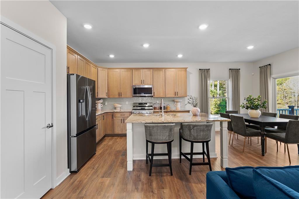 229 Lola Court McKees Rocks, PA 15136 - Photo 9 of 23 a kitchen with stainless steel appliances granite countertop a refrigerator a sink dishwasher a dining table and chairs with wooden floor