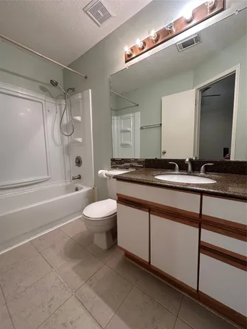 a bathroom with a granite countertop sink a toilet a mirror and shower
