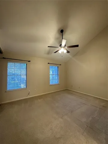 an empty room with windows and fan