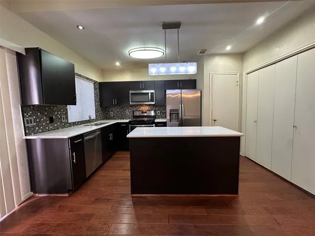 a kitchen with kitchen island stainless steel appliances a sink counter space and wooden floor