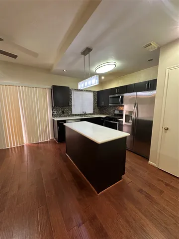 a kitchen with stainless steel appliances granite countertop a sink a stove and a wooden floors