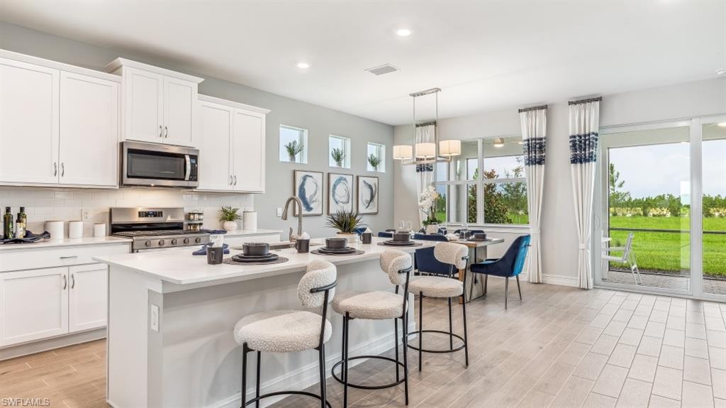 17911 Shade Tree Loop Babcock Ranch, FL 33982 - Photo 7 of 44 a kitchen with a table chairs microwave and cabinets