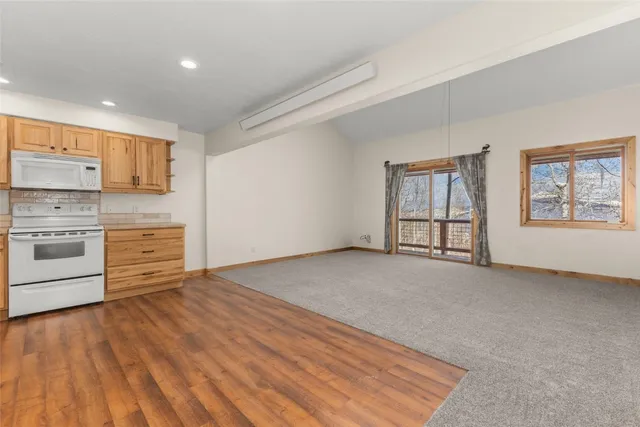 a view of a kitchen with wooden floor electronic appliances and windows