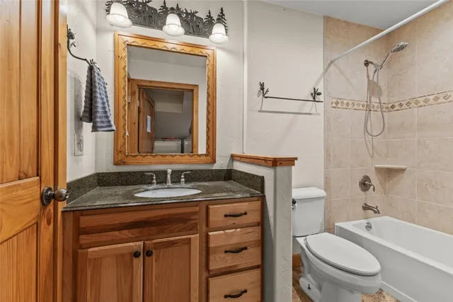 a bathroom with a granite countertop sink toilet mirror vanity and bathtub
