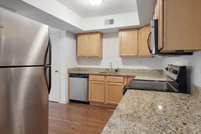 a kitchen with kitchen island granite countertop a sink cabinets and stainless steel appliances