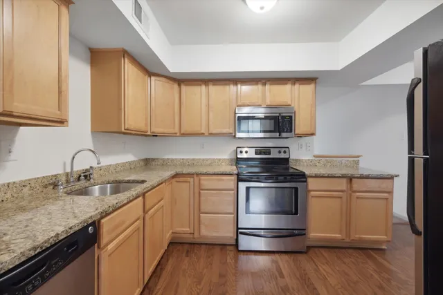 a view of kitchen with stainless steel appliances wooden floor and a counter top space