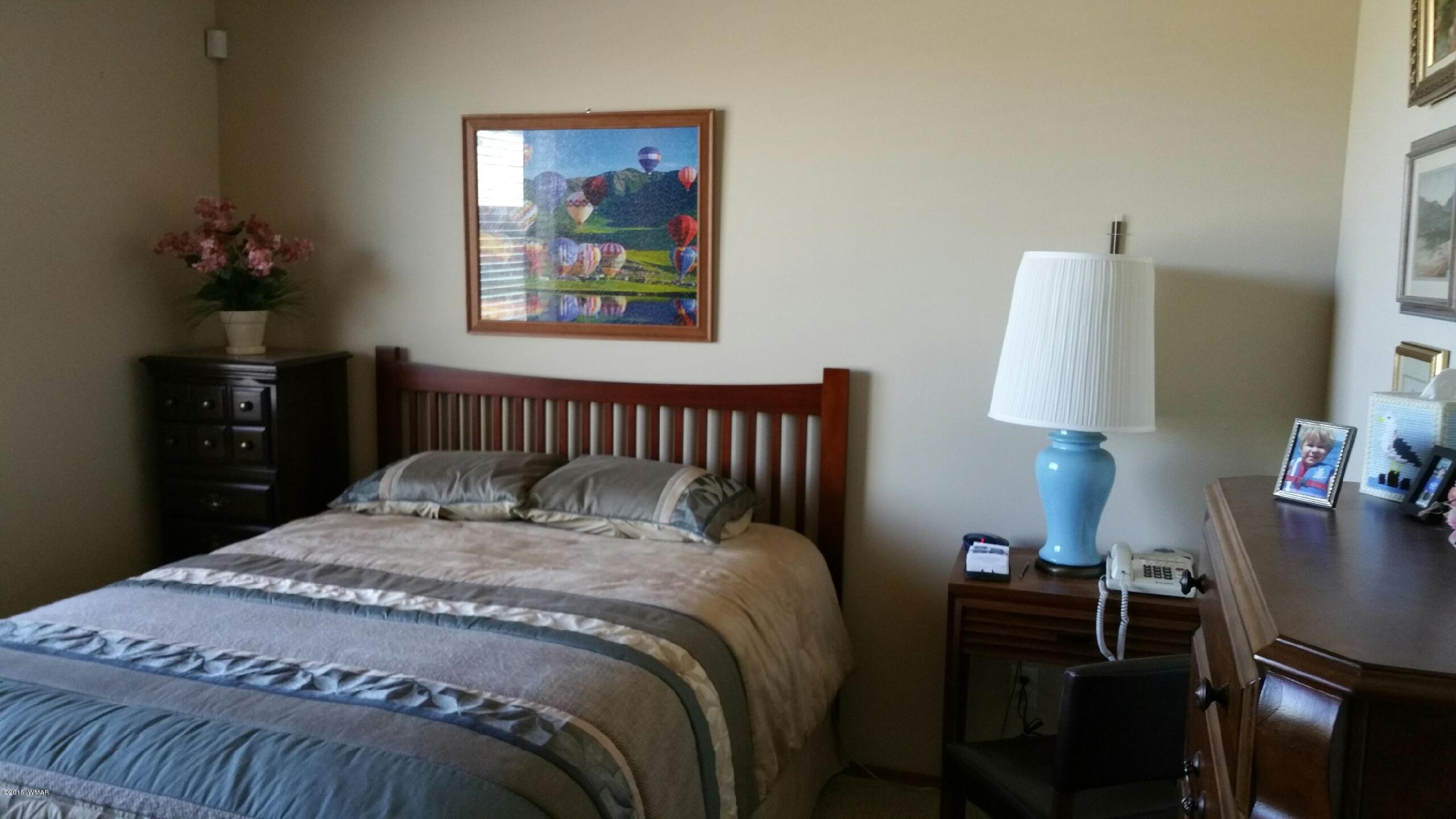 2831 West Villa Loop, Unit 102 Show Low, AZ 85901 - Photo 6 of 6 a bedroom with a bed and a lamp on table