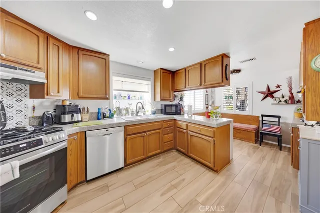 a kitchen with stainless steel appliances granite countertop wooden cabinets stove top oven and sink