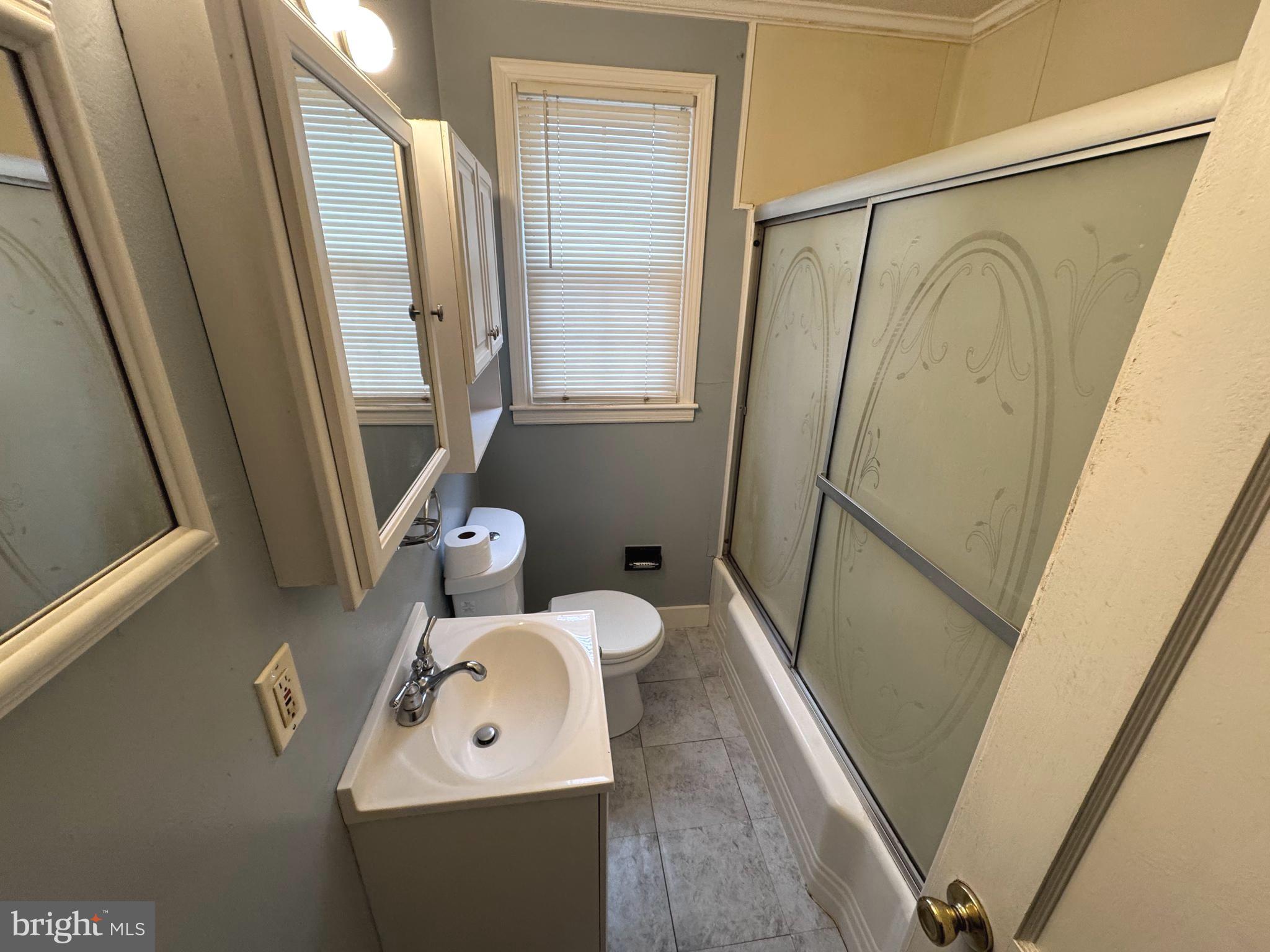 1705 Summit Avenue Baltimore, MD 21227 - Photo 4 of 7 a bathroom with a sink a mirror and a shower