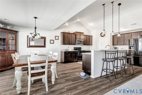 a kitchen with stainless steel appliances a dining table chairs stove and cabinets