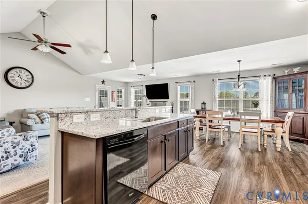 a kitchen with stainless steel appliances kitchen island granite countertop a table chairs in it and wooden floors