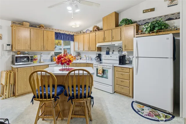 a kitchen with stainless steel appliances a dining table chairs a refrigerator and microwave