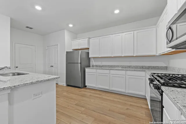 a kitchen with white cabinets sink and stainless steel appliances