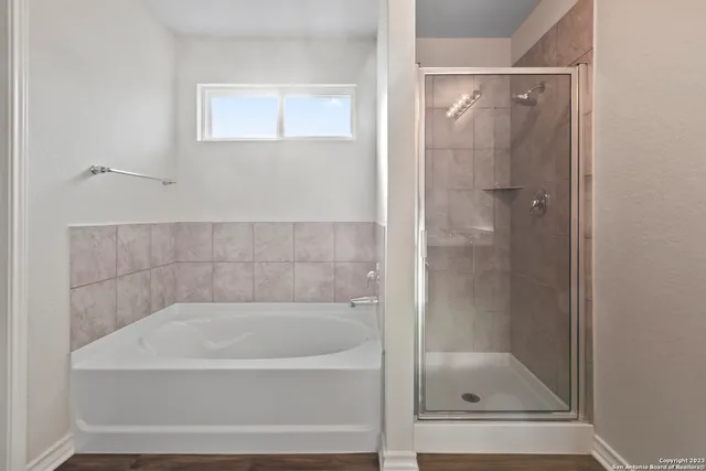 an empty room with wooden floor mirror and windows