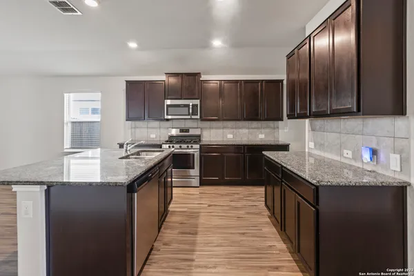 a kitchen with stainless steel appliances granite countertop wooden cabinets a sink and a stove