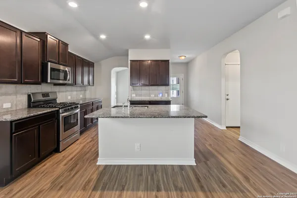 a large kitchen with stainless steel appliances granite countertop a stove a sink and a microwave