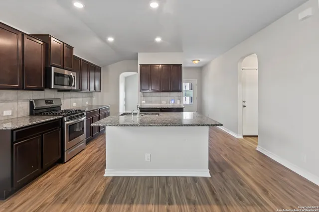 a large kitchen with stainless steel appliances granite countertop a stove a sink and a microwave