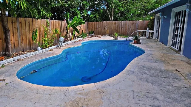 a view of a backyard with table and chairs a barbeque and wooden fence