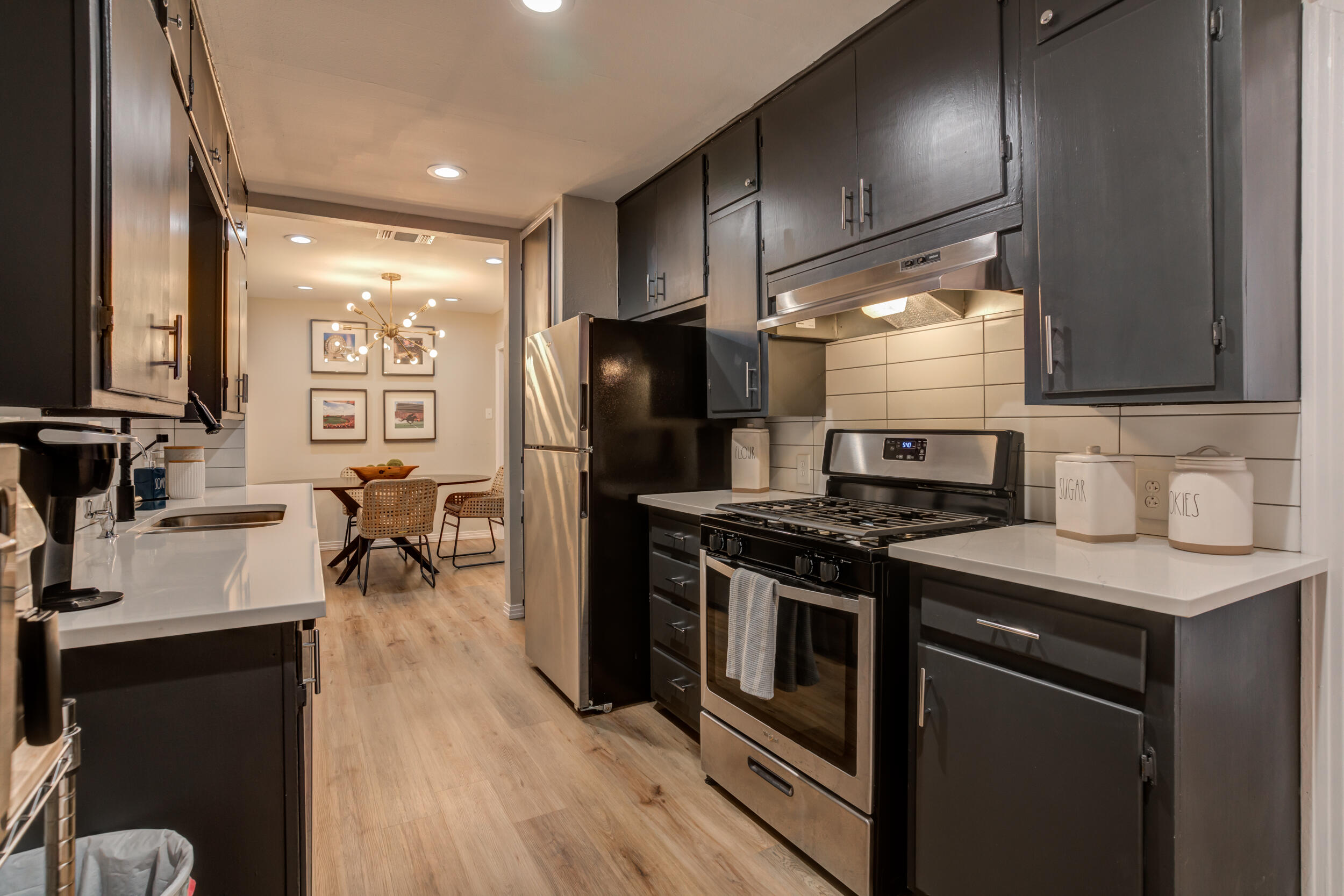 2802 39th Street Lubbock, TX 79413 - Photo 17 of 61 a kitchen with stainless steel appliances a stove a sink dishwasher a refrigerator white cabinets and wooden floor