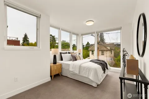a bedroom with a bed a large window with table and chairs