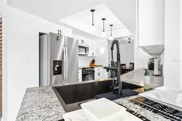 a living room with stainless steel appliances kitchen island granite countertop furniture and a rug