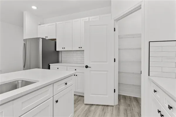 a kitchen with white cabinets and refrigerator