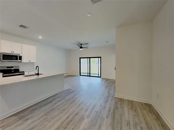 a view of a kitchen with wooden floor and electronic appliances