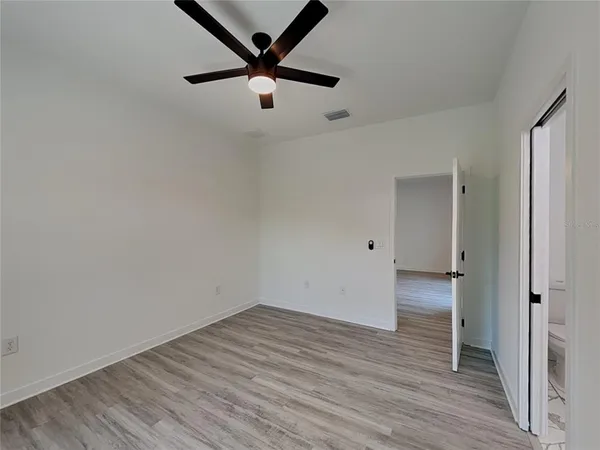 an empty room with wooden floor and a ceiling fan