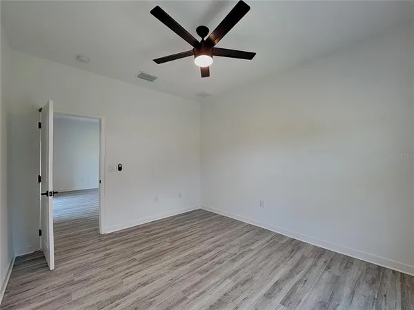 an empty room with wooden floor and a ceiling fan