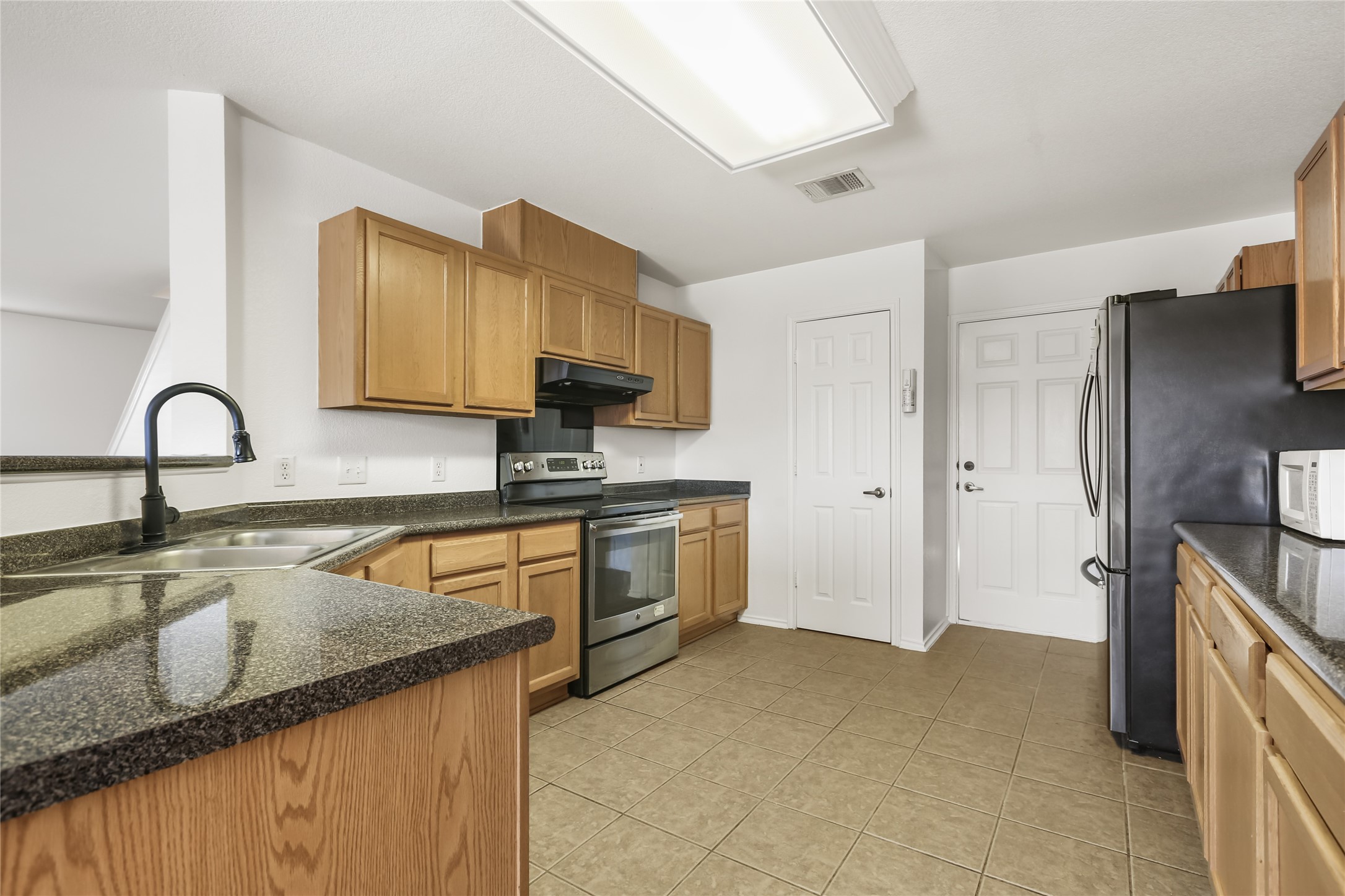 2010 Ashberry Trail Georgetown, TX 78626 - Photo 4 of 24 Kitchen featuring stainless steel appliances, wood finish cabinets, and light tile patterned flooring