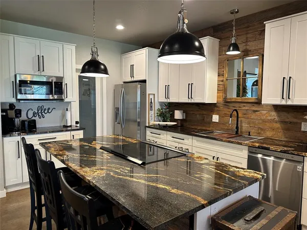 a kitchen with stainless steel appliances kitchen island granite countertop a stove and a refrigerator